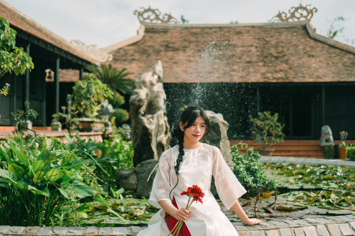 A woman in a white dress sitting on a stone wall